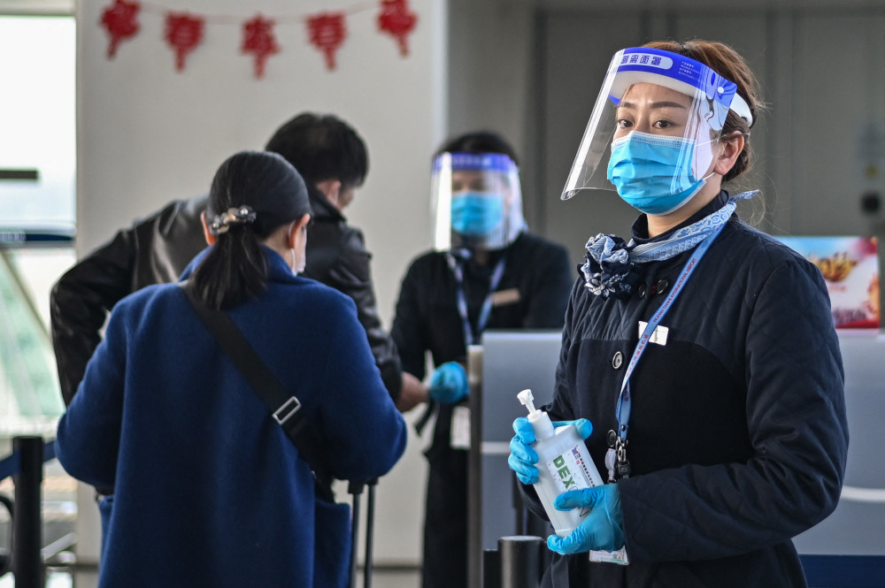 An airline worker wearing a face mask waits to give passengers alcohol gel to wash their hands at Tianhe International Airport in Wuhan, Chinau00e2u20acu2122s central Hubei province February 12, 2021. u00e2u20acu201d AFP pic 