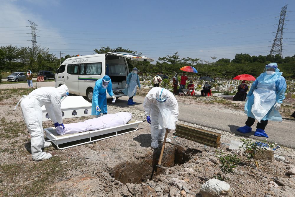Workers wearing personal protective equipment bury the body of a Covid-19 victim at a cemetery in Shah Alam February 25, 2021. u00e2u20acu201d Picture by Yusof Mat Isa