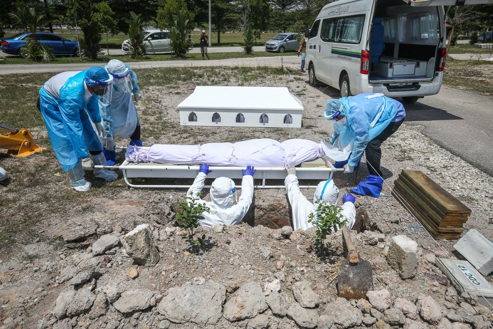 Workers wearing personal protective equipment bury the body of a Covid-19 victim at a cemetery in Shah Alam February 25, 2021. u00e2u20acu201d Picture by Yusof Mat Isa