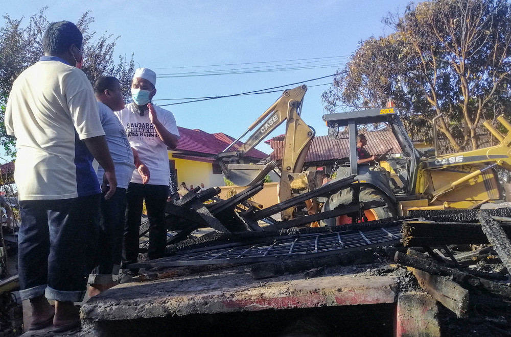 Ebit Lew (right) and Mohd Yazid Mohd Nor survey the damage done to the razed house in Kampung Pengkalan Nangka in Pengkalan Chepa, February 10, 2021. u00e2u20acu201d Bernama pic 