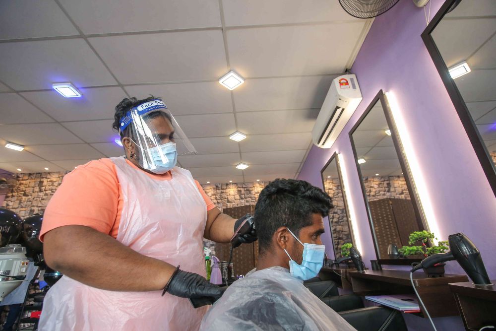 Hairdresser C. Nageswaran gives his customer a haircut at the Triple Hair Studio in Ipoh February 5, 2021. — Picture by Farhan Najib