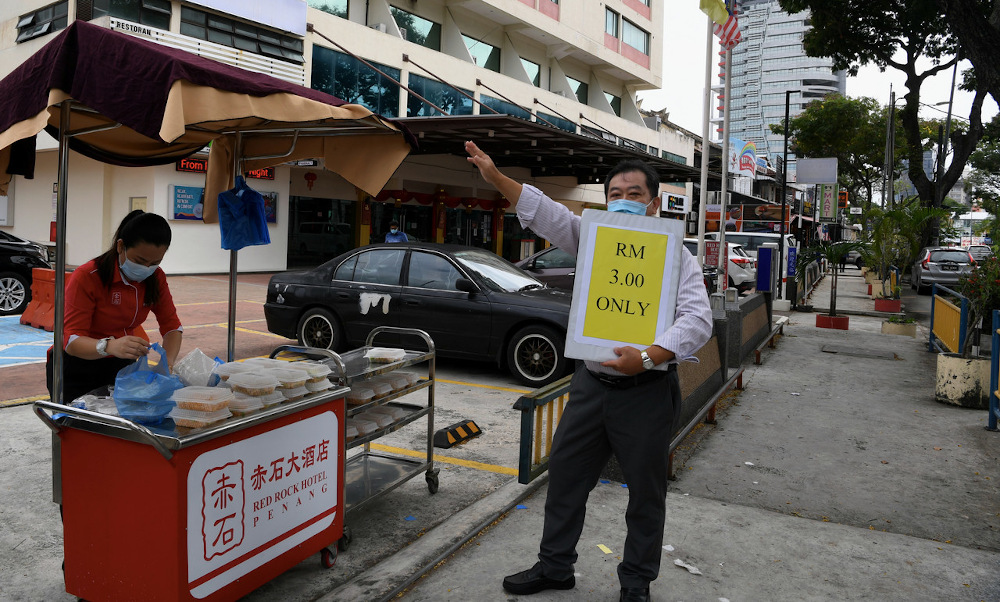 Jeffrey Lim (right) waving down customers to buy from the hotelu00e2u20acu2122s roadside food stall. u00e2u20acu201d Bernama pic