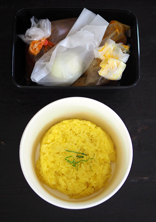 The 'pulut kuning' is packed in a container that makes it easy to eat on the go with the 'rendang' on the side.