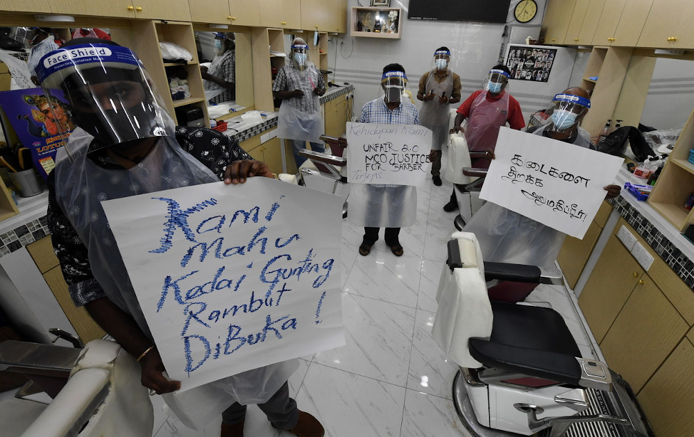 Barbers in Penang hold handwritten signs pleading for the government to allow them to operate during the movement control order February 1, 2021. u00e2u20acu201d Bernama picn