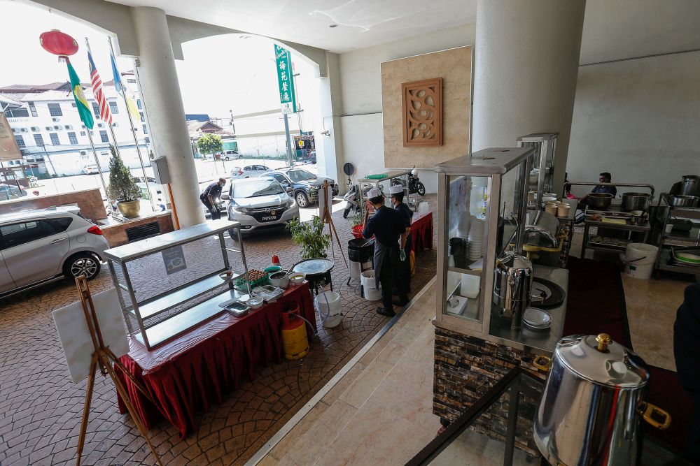 Patrons pick up food from the hawker stalls lining the hotel's entrance in George Town February 3, 2021. — Picture by Sayuti Zainudin