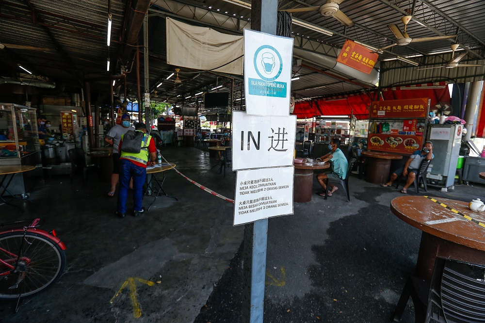 Police officers checking the logbook entry during an operation here at a restaurant in Jalan Raja Uda February 17, 2021. u00e2u20acu2022 Picture by Sayuti Zainudin