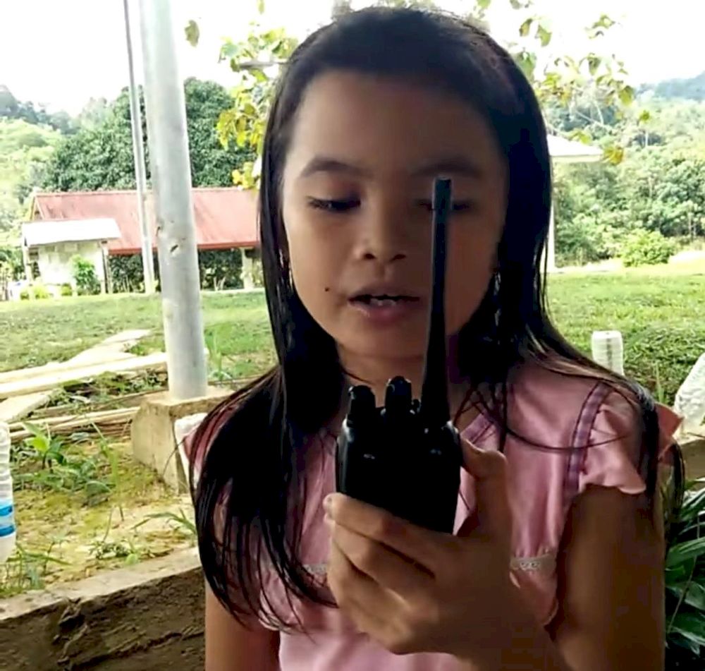 A student uses a walkie-talkie to practice  multiplication tables.