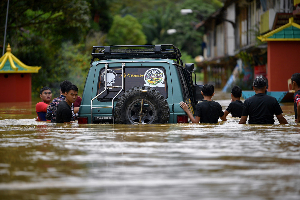Residents of Kampung Tebakang Dayak near Serian try to move a four-wheel drive vehicle after the village was hit by floods, February 4, 2021. u00e2u20acu201d Bernama pic 