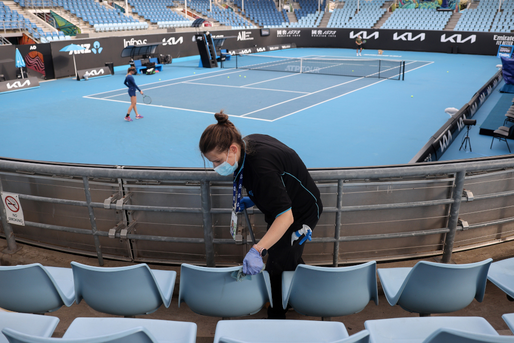 A worker cleans the seating areas on court 3 at Melbourne Park February 4, 2021, as preparations for the Australian Open were thrown into chaos when up to players and officials were told to isolate and get tested after a hotel staff member tested positive