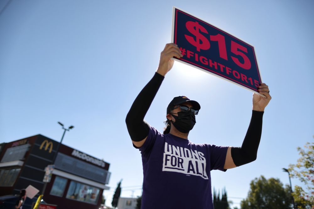 A man holds up a minimum wage sign at a rally in Los Angeles February 18, 2021. u00e2u20acu201d Reuters picn