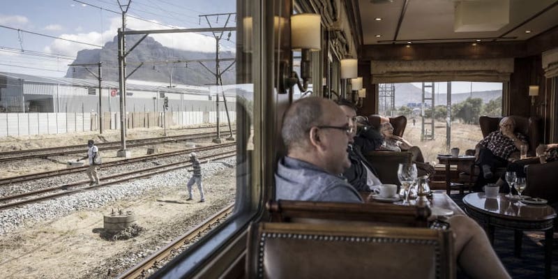 Blue Train passengers enjoy drinks in the observation car as the train slowly makes its way through the outskirts of Cape Town. u00e2u20acu201d AFP pic