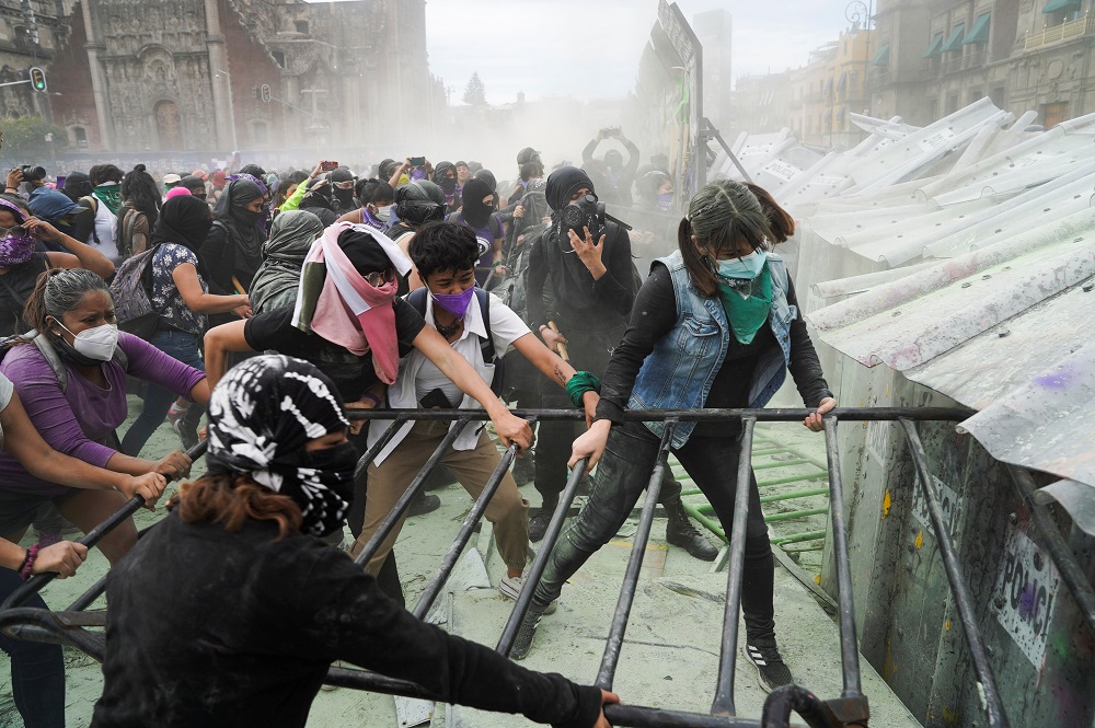 Women hold a metal fence during a protest outside the National Palace to mark International Women’s Day in Mexico City March 8, 2021. — Reuters pic