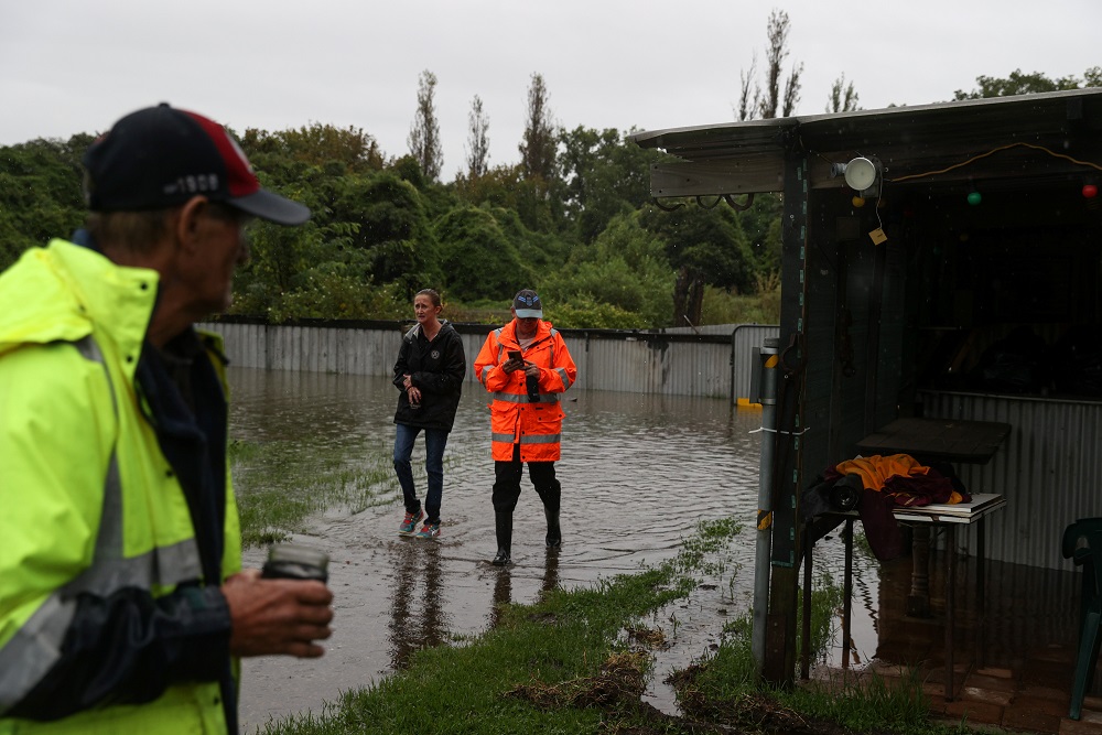 Local residents walk through their property to check on a house while floodwaters rise in the suburb of Riverstone in Sydney March 22, 2021. — Reuters pic
