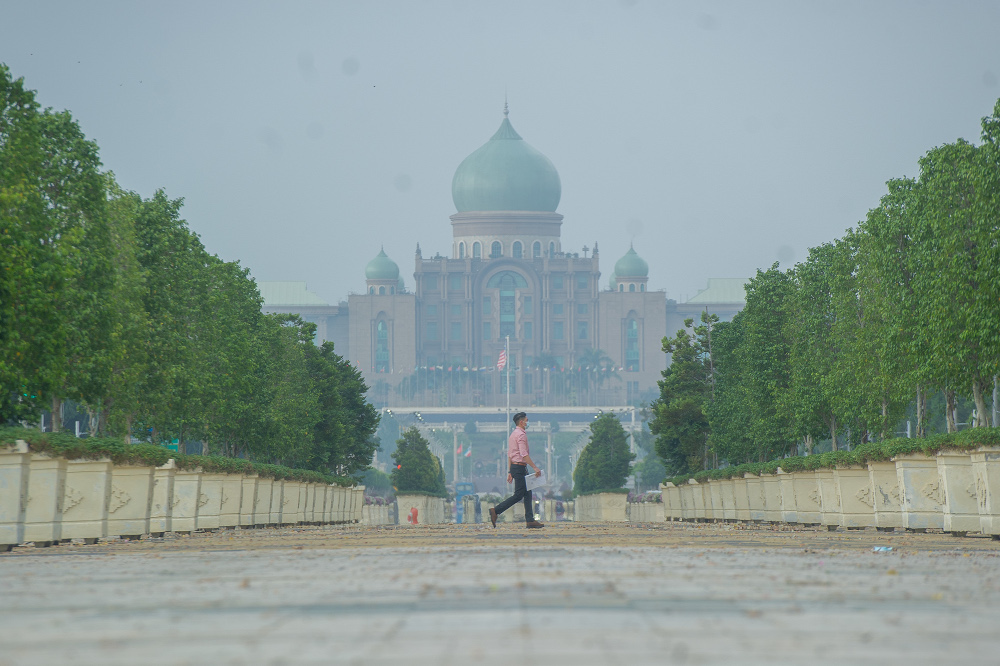 Pedestrians crossing the street against a hazy backdrop of the Perdana Putra building at Putrajaya Boulevard in Putrajaya March 2, 2021. u00e2u20acu201d Picture by Shafwan Zaidon