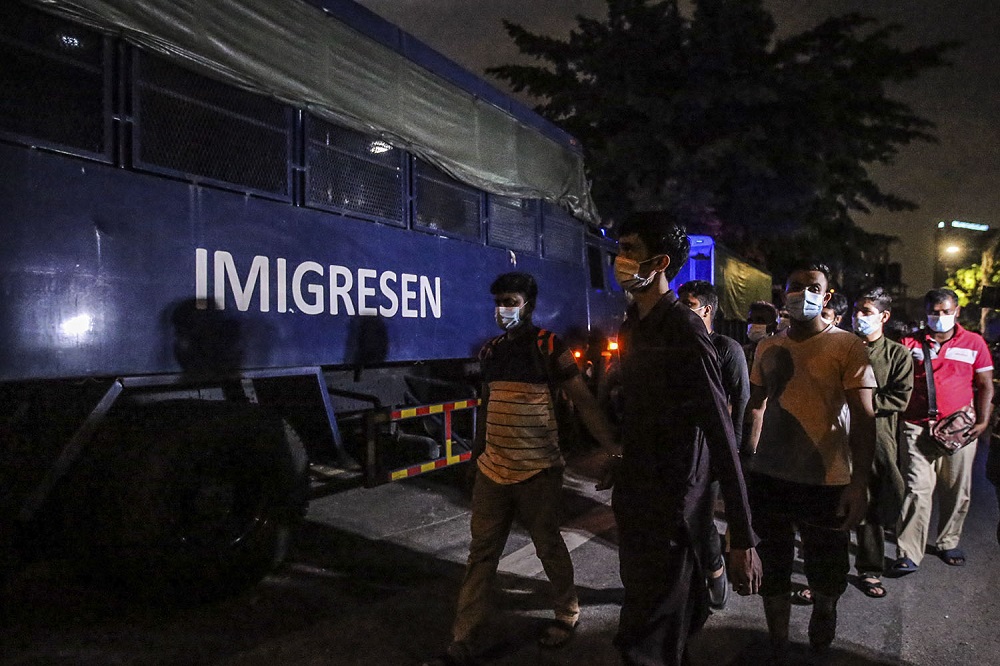 Foreigners nabbed during a raid are led to an Immigration Department vehicle, in Kuala Lumpur March 6, 2021.