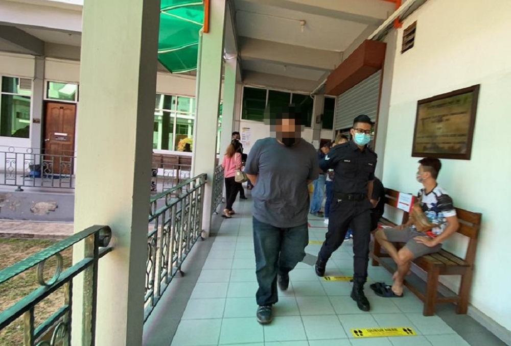 A policeman escorts the accused (left) at the court compound. u00e2u20acu201d Borneo Post Online