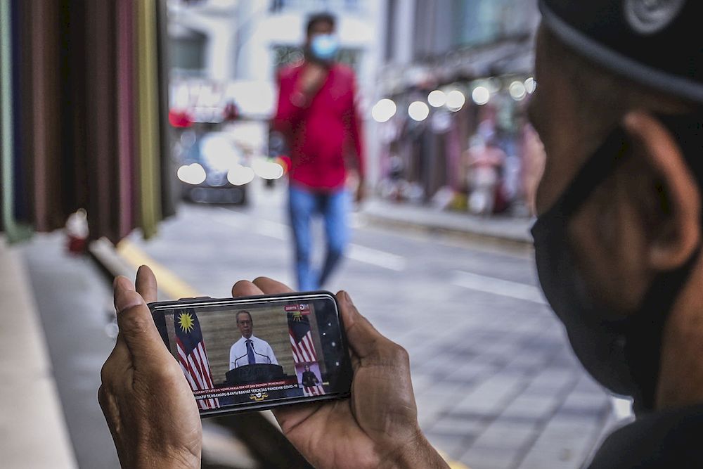 A store keeper at Jalan Tuanku Abdul Rahman watching the live telecast of Prime Minister Tan Sri Muhyiddin Yassin announcing the Pemerkasa programme, March 17, 2021. u00e2u20acu2022 Picture by Hari Anggara