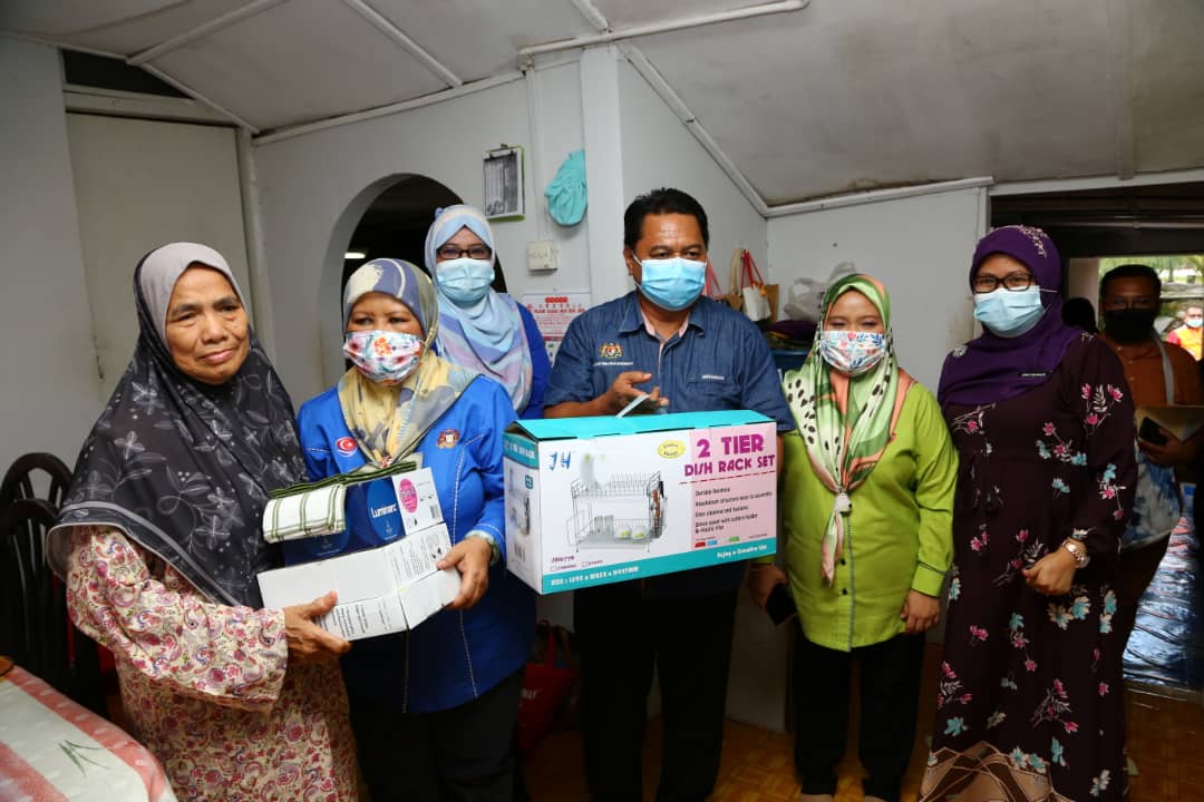 Johor Women, Family and Community Development Committee chairman Zaiton Ismail (second from left) and Johor Welfare Department director Mohamad Hapil (centre) hand over donations to Azizah Omar (left) at her house in Johor Baru. u00e2u20acu201d Picture by Ben Tan