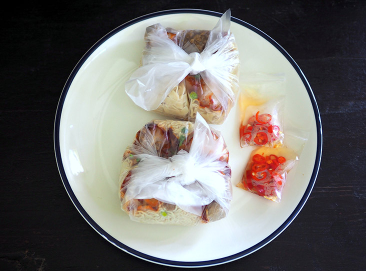 Your takeaway 'kolo mee' is packed in plastic and served with pickled red chillies.