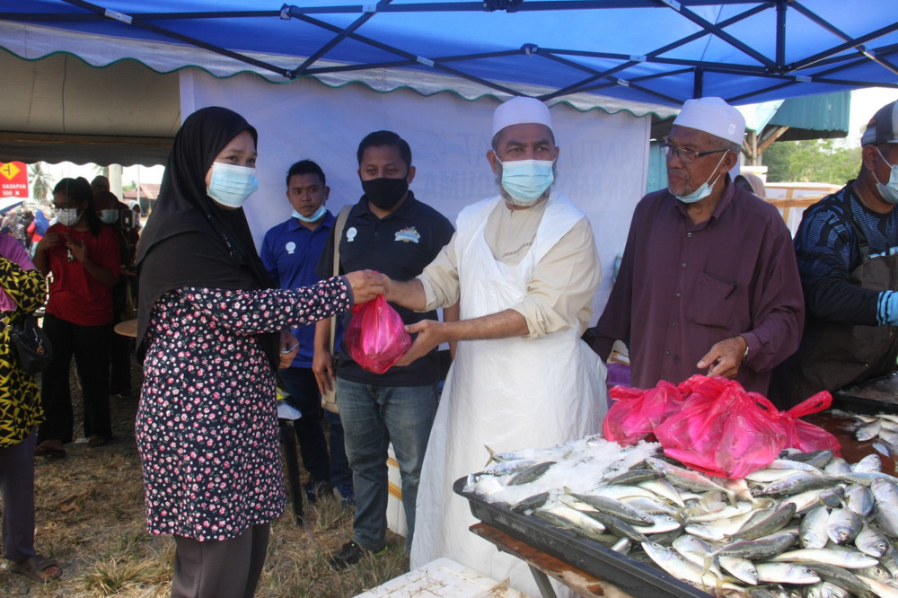 LKIM chairman Datuk Syed Abu Hussin Hafiz Syed Abdul Fasal hands over fish to Normah Majid at the Prihatin Bukit Gantang Mobile Shop Programme in Bukit Gantang, March 4, 2021. u00e2u20acu201d Bernama pic 