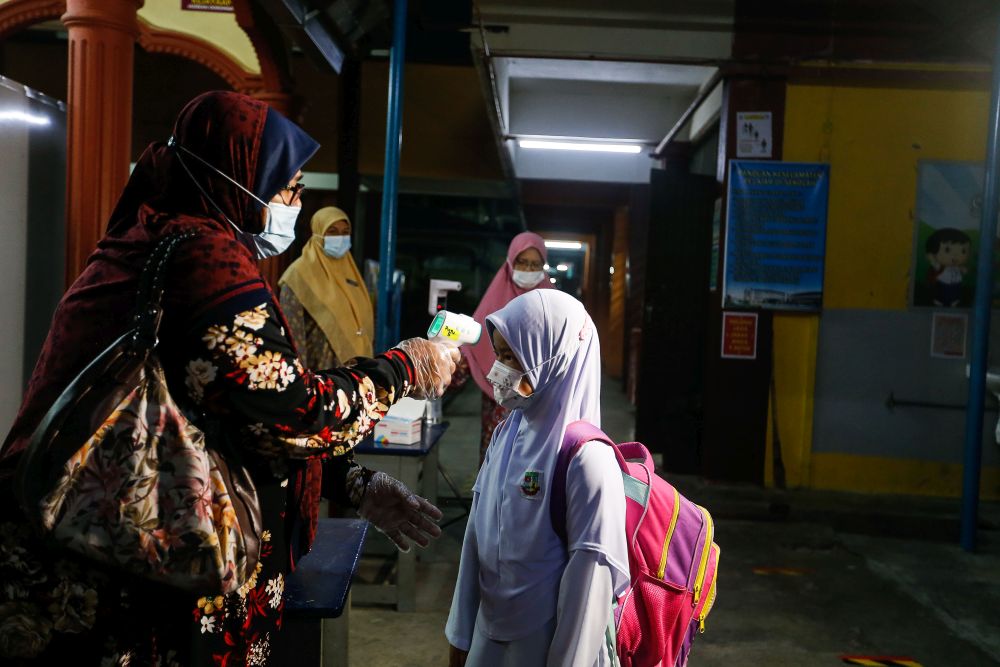 A Sekolah Kebangsaan Penaga student has her temperature checked on her first day back at school in Penang March 1, 2021. u00e2u20acu201d Picture by Sayuti Zainudin