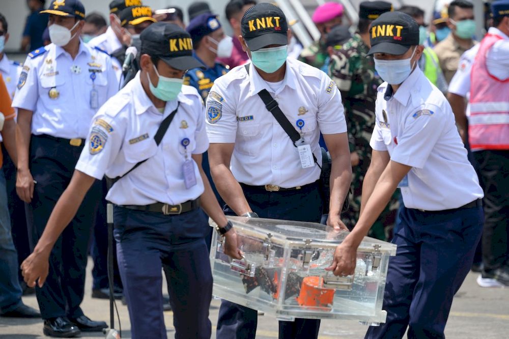 Indonesian officials carry a box contain cockpit voice recorder (CVR or blackbox) at the port in Tanjung Priok in Jakarta, on March 31, 2021, after it was recovered during search operations for the Sriwijaya Air Boeing 737-500 passenger jet which disappea