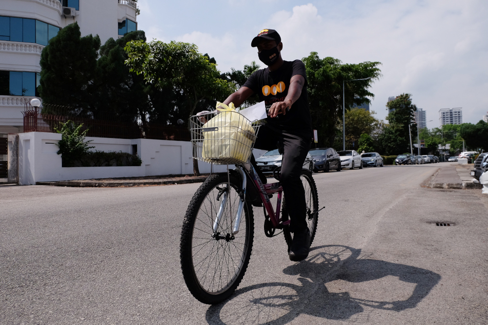 A delivery staff delivers the food to a nearby customer on bicycle. — Picture by Steven Ooi KE