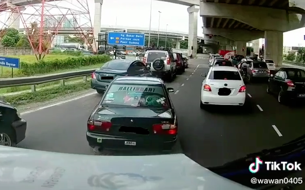 The truck was forced to trail behind the black Proton Wira for some time before it finally cleared the traffic jam. — Screengrab via TikTok/wawan0405