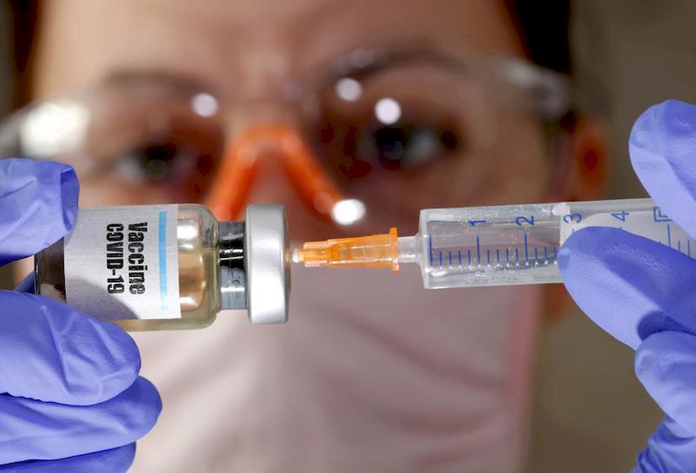 A woman holds a small bottle labelled with a ‘Vaccine COVID-19’ sticker and a medical syringe in this illustration taken April 10, 2020. — Reuters pic