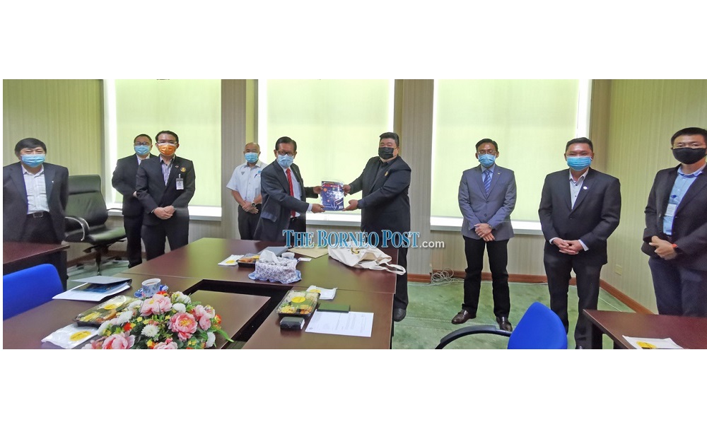 Hii (fourth right) presents a memento to Lee during the courtesy call. u00e2u20acu201d Borneo Post Online pic