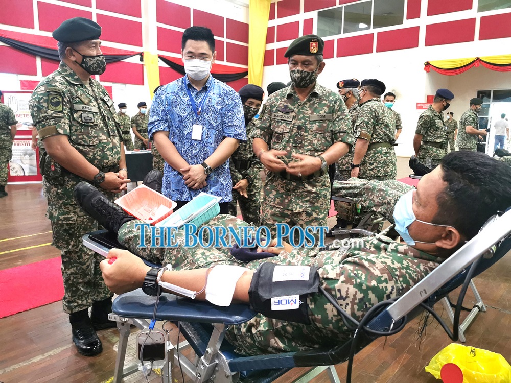 Mardzuki (standing, right) and Dr Wong on his right observe a soldier giving blood during the event. u00e2u20acu201d Borneo Post Online pic