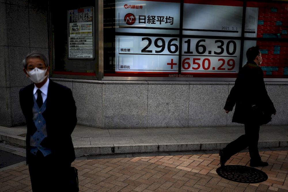 A man stands in front of an electronic quotation board displaying the numbers of share prices on the Tokyo Stock Exchange in Tokyo on March 1, 2021. u00e2u20acu201d AFP pic