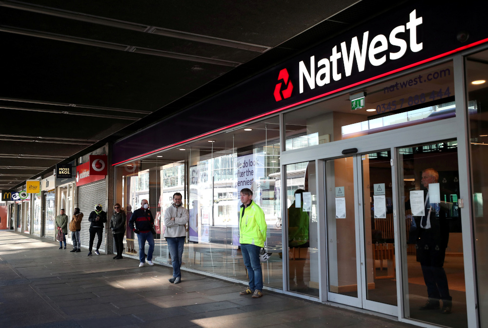 People maintain social distance while they queue outside a Natwest bank as the spread of Covid-19 continues, in London March 26, 2020. u00e2u20acu201d Reuters pic