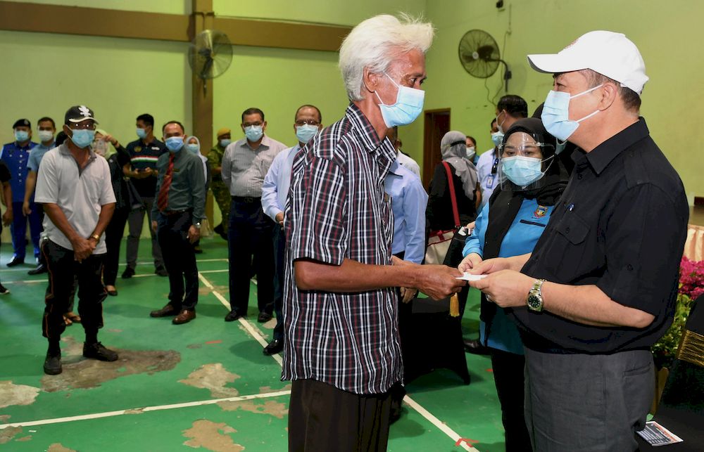 Sabah Chief Minister Datuk Seri Hajiji Noor (right) presenting donations to fire victims of Kampung Lok Urai Pulau Gaya during a ceremony at the Sembulan Multipurpose Hall, Kota Kinabalu, March 17, 2021. u00e2u20acu201d Bernama pic