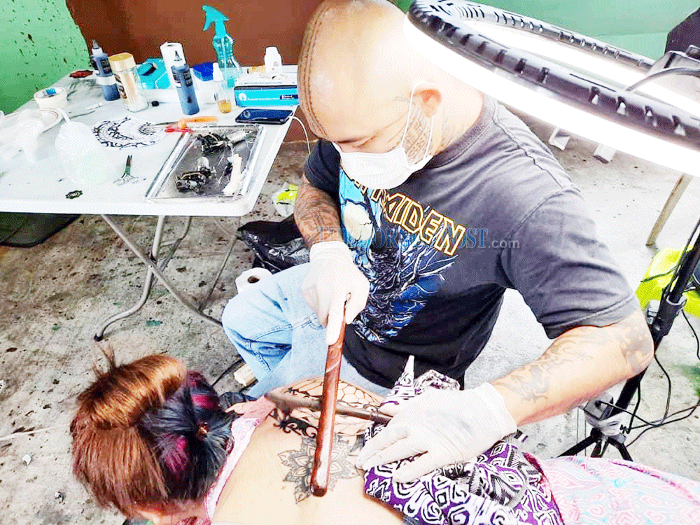 Jeremy Lo tattooing a female customer at his studio. u00e2u20acu2022 Borneo Post pic