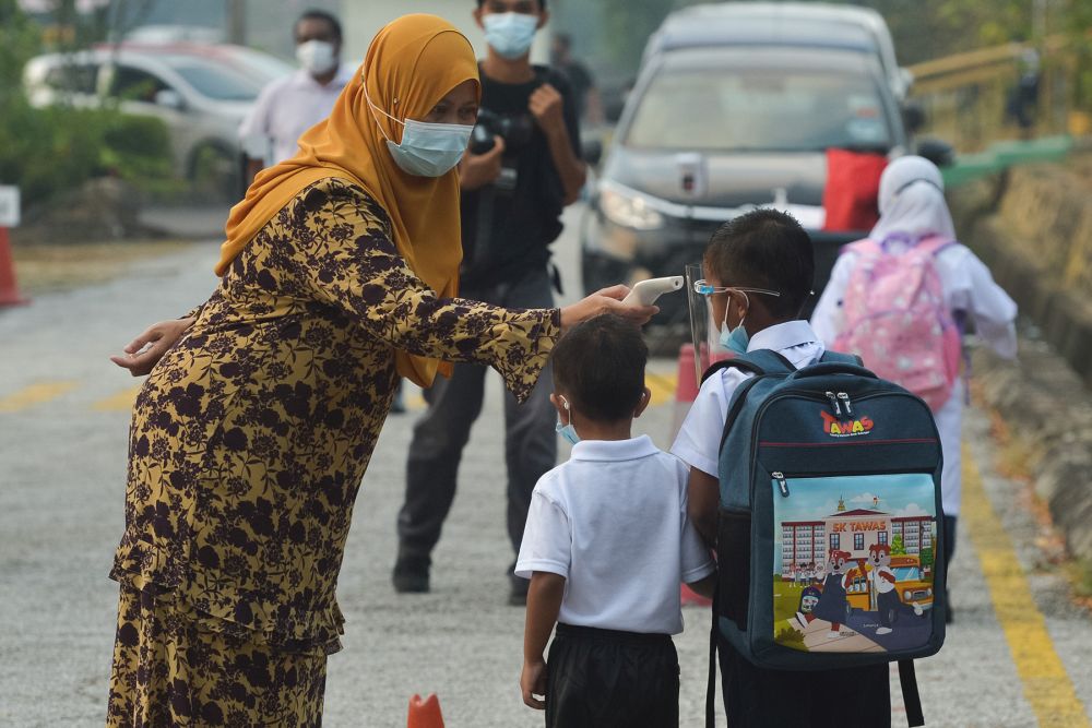 Sekolah Kebangsaan Seksyen 16 students have their temperature checked on their first day back at school in Shah Alam March 1, 2021. u00e2u20acu201d Picture by Miera Zulyana