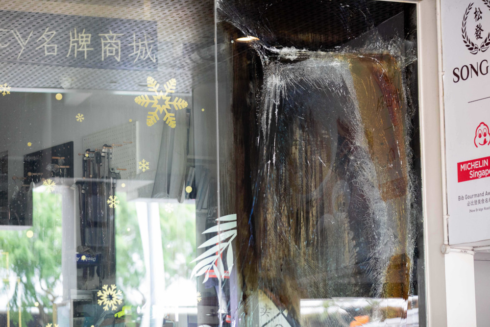 Burn marks seen on the glass panel of Luxury City store in Chinatown Point on March 12, 2021. — TODAY pic