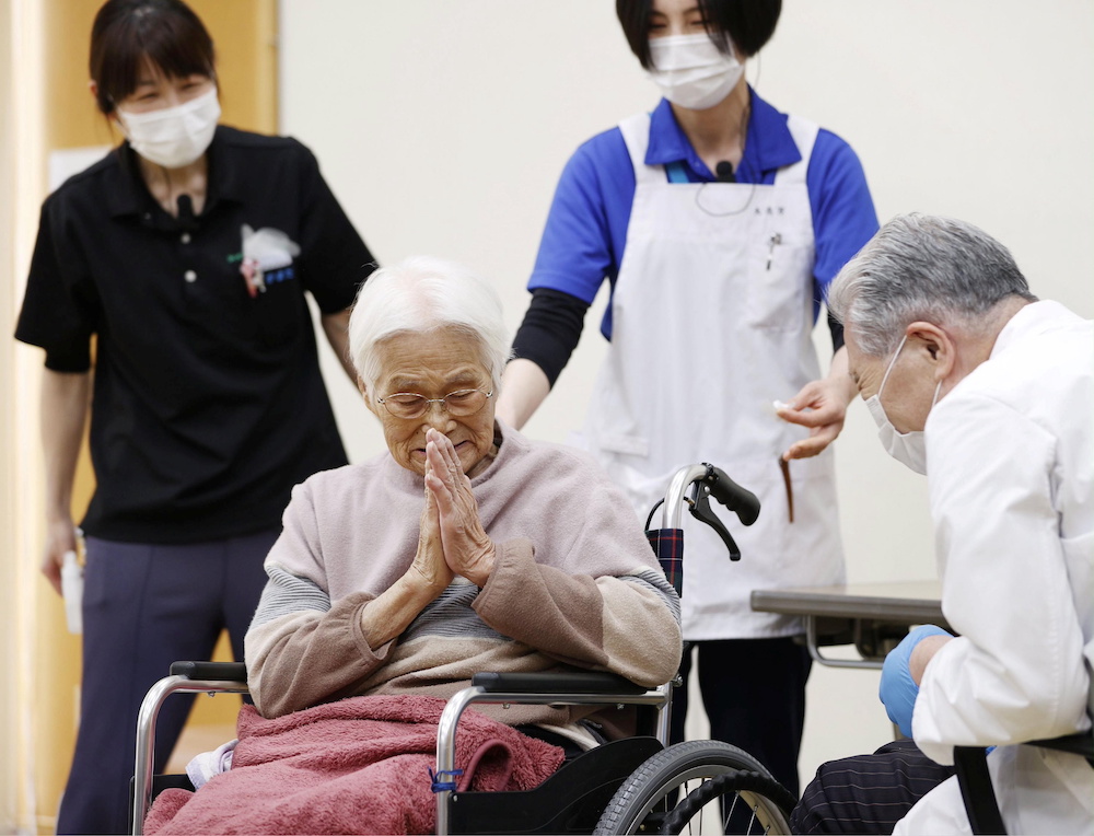 An elderly woman gestures to express gratitude after receiving a coronavirus disease (Covid-19) vaccination in Itami, western Japan April 12, 2021, in this photo released by Kyodo. u00e2u20acu201d Kyodo/via Reuters