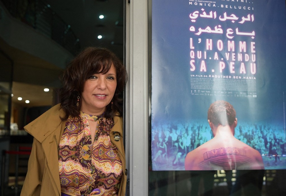 Tunisian director and screenwriter, Kaouther Ben Henia, poses for a picture in front of the poster of her film u00e2u20acu02dcThe man who sold his skinu00e2u20acu2122 during its first screening in the country, in the capital Tunis March 30, 2021. u00e2u20acu201d AFP pic