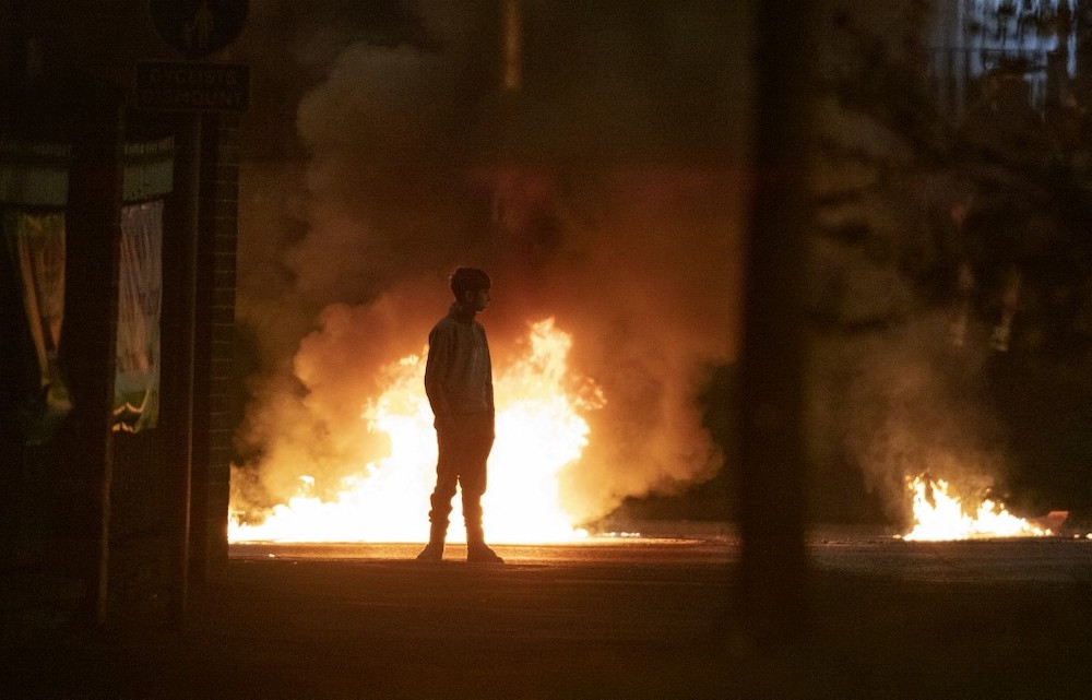 A boy stands and looks on as flames and smoke rises behind him in Northern Ireland on April 3, 2021. u00e2u20acu201d AFP pic