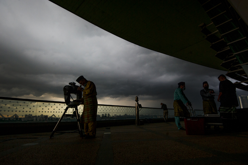 An officer from the Federal Territories Mufti Office looks through a telescope to perform u00e2u20acu02dcrukyahu00e2u20acu2122, also known as the sighting of the new moon for Ramadan, at the Putrajaya International Convention Centre April 12, 2021. u00e2u20acu201d Picture by Shafwan Zaidon