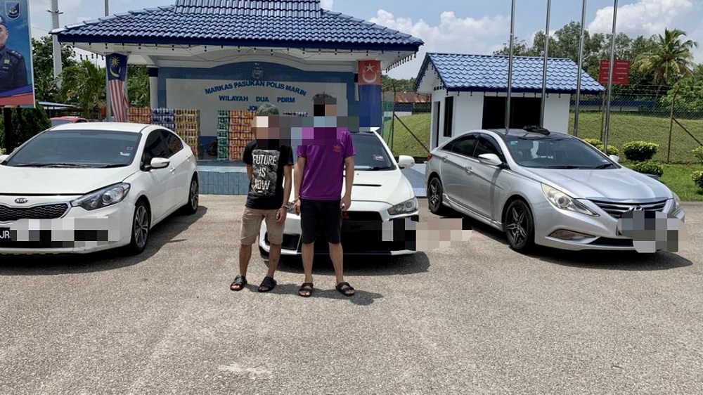 The two suspects with the cars at the Region Two Marine Police Force headquarters in Tampoi, Johor Baru. — Picture courtesy of Region Two Marine Police Force 