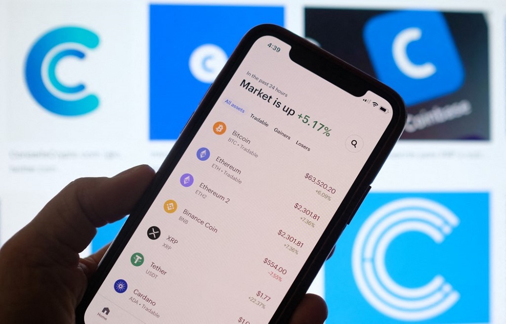 This illustration photo shows the Coinbase logo in the background as a person checks cryptocurrencies prizes on a smartphone in Los Angeles on April 13, 2021. u00e2u20acu201d AFP pic