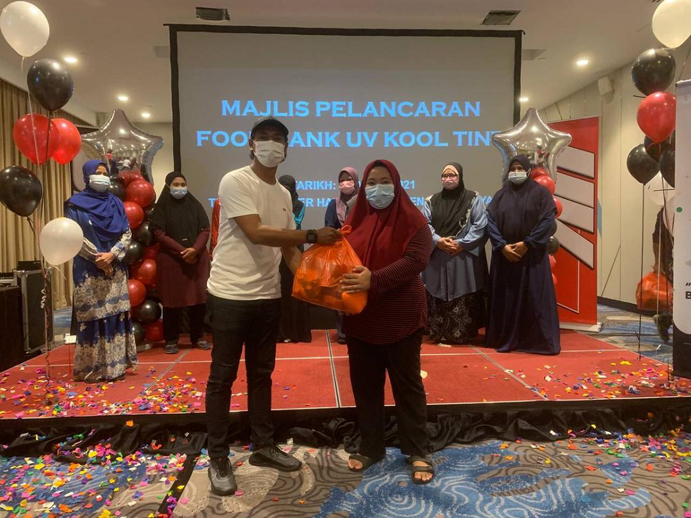 TMK Industries managing director Mohd Fadzli Che Harun (left) presenting a food basket to the poor during the launching of UV Kool Tint’s food bank recently. — Picture courtesy of UV Kool Tint