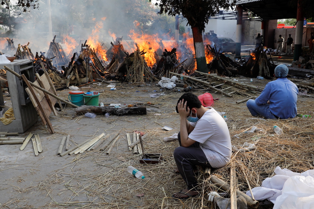Family members sit next to the burning funeral pyres of those who died from the coronavirus disease (Covid-19), at a crematorium in New Delhi, India April 26, 2021. u00e2u20acu201d Reuters pic