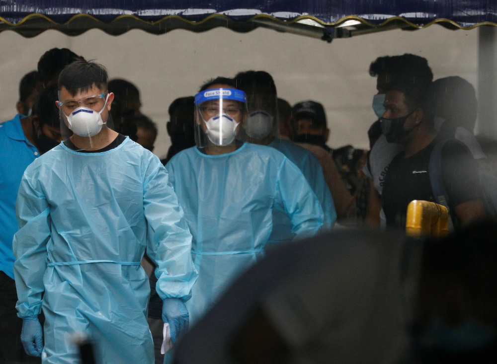 Personnel in protective garment usher a group of migrant workers to take a bus to a government quarantine facility after workers were tested positive for Covid-19 at Westlite Woodlands dormitory in Singapore April 22, 2021. u00e2u20acu201d Reuters pic