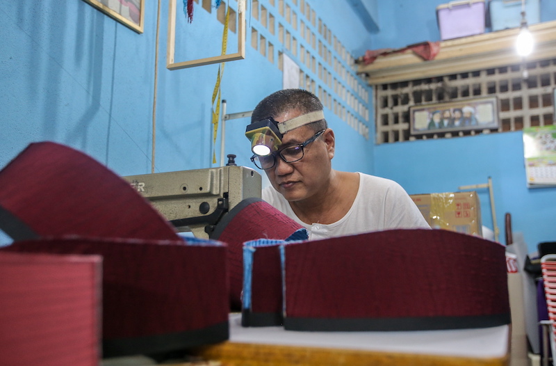 With a torchlight on his head, songkok maker Hamzah Irzal can complete one songkok in 30 minutes. u00e2u20acu201d Picture by Farhan Najib