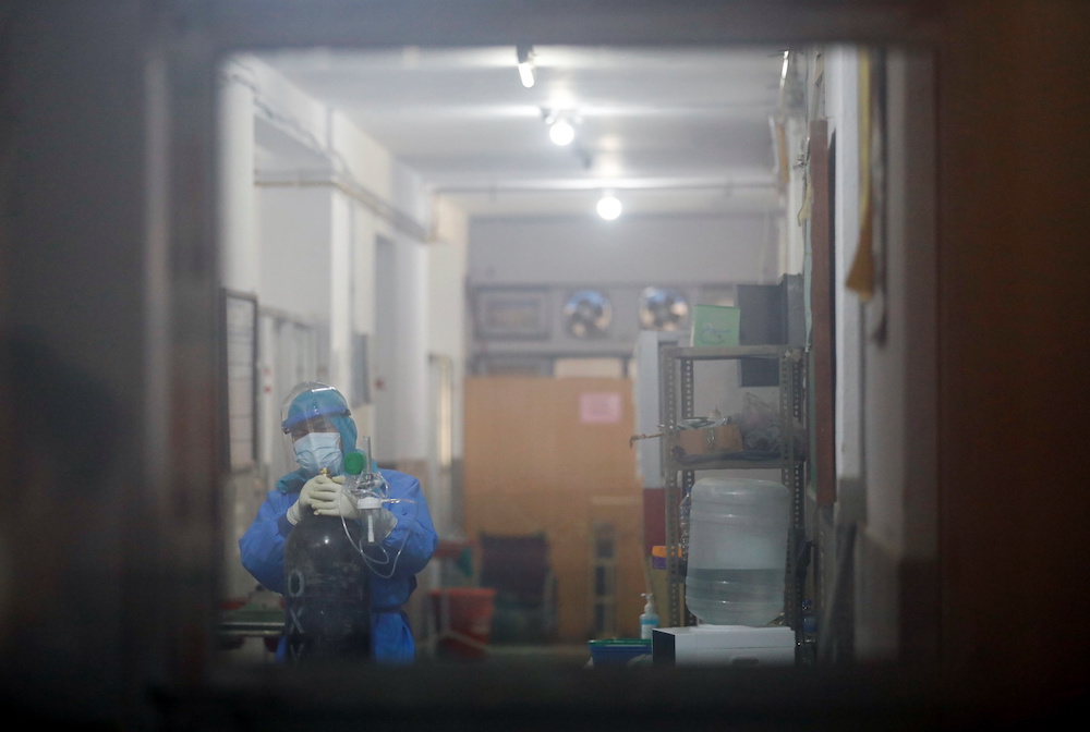 A health worker is seen through the window as he drags an oxygen cylinder towards the Covid ward as the major second wave of Covid-19 surges in Kathmandu, Nepal April 26, 2021. u00e2u20acu201d Reuters pic