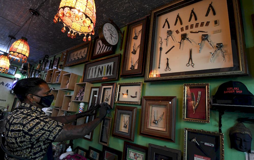 S. Singgara Vella cleaning a glass frame stacked with barber hardware at his Verlarz Classic Barbershop on Ah Quee Street in George Town, April 24, 2021. u00e2u20acu201d Bernama pic