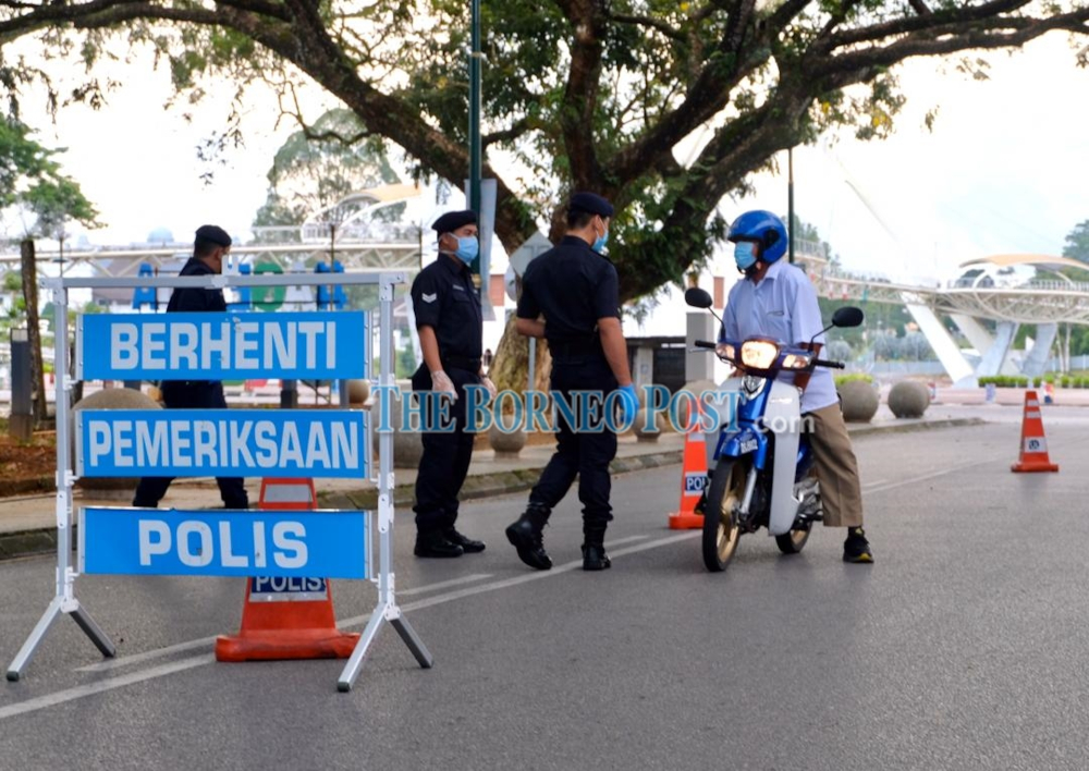 Policemen stopping a motorcyclist at an MCO roadblock near the Kuching Old Courthouse. u00e2u20acu201d Borneo Post Online picn